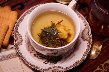 Holiday evening at home - porcelain cup of best herbal tea, antique candle in candlestick, old letters and jar of honey