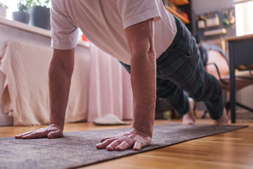 Cheerful senior hispanic man doing a side plank exercise at living room.