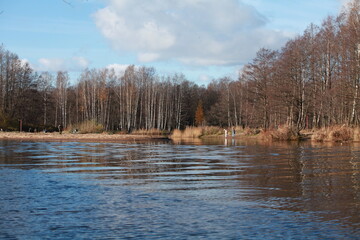 river autumn landscape, bare trees, warm sunny day people resting in nature