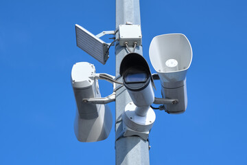 White CCTV camera and loudspeaker on the pole.