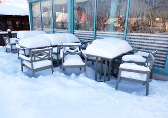 tables and chairs in the cafe littered with snow