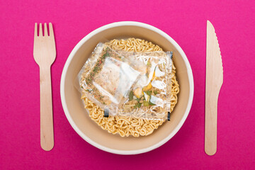 Opened Package with Uncooked Instant Noodles on Pink Background. Raw Pasta. Dry Asian Fast Food. Quick Lunch