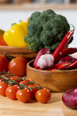 Fresh ripe vegetables in wooden bowls and on the kitchen table prepared for cooking homemade stew