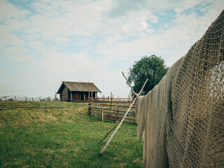 Old wooden building, house, seine on a rope, summer, green grass, cattle pen, light clouds