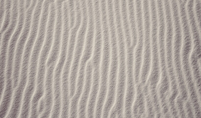 Fototapeta na wymiar Fine dune sand. Shapes formed by the wind. Background from above.
