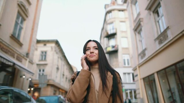 Close up portrait of attractive woman having a phone talk in the city street. Serious beautiful woman standing on street. . High quality 4k footage