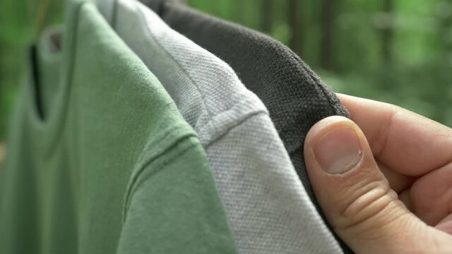 colorful organic cotton t shirts on hangers outdoor. sustainable fashion concept, eco fashion. textile and fashion industries, environmental problems, recycling, synthetic agricultural chemicals