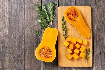 Butternut squash slices with  rosemary on a wooden table, copy space for your text.