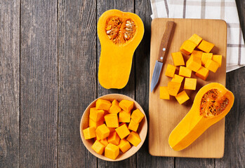 Diced butternut squash on wooden cutting board, top view. Cooking cake making process. - obrazy, fototapety, plakaty