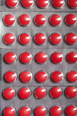 Blisters with red tablets. On a light background. Close-up.