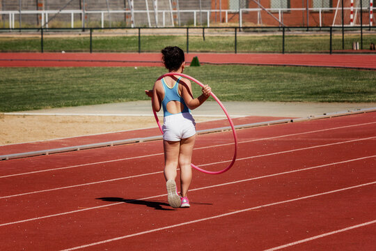 Niña con el aro hula hula como parte de su entrenamiento de atletismo en las instalaciones deportivas.