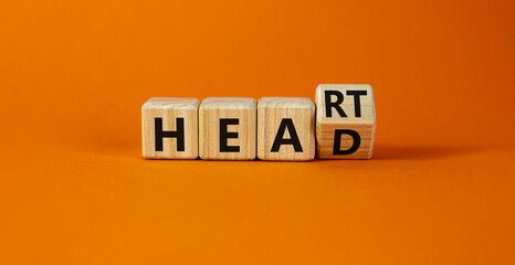 Heart or head symbol. Turned a wooden cube and changed the word head to heart. Beautiful orange table, orange background, copy space. Medical, lyfestyle and heart or head concept.