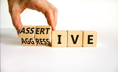 Aggressive or assertive symbol. Businessman turns wooden cubes, changes the word Aggressive to Assertive. Beautiful white background, copy space. Business, psychological aggressive assertive concept.