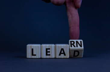 Learn and lead symbol. Businessman turns a wooden cube and changes the word learn to lead....