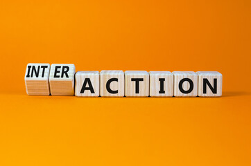 Action or interaction symbol. Turned wooden cubes and changed the word action to interaction. Beautiful orange background, copy space. Business and action or interaction concept.