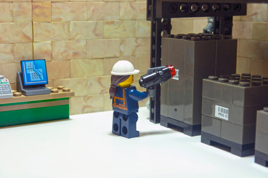Warehouse worker, reading a label automatically with a reader device on packages stored on a warehouse shelf
