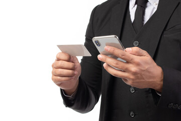 Handsome business man in black suit holding credit card and using smartphone for online shopping isolated on white background. Business, technology, ecommerce and online payment concept.