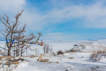 Winter landscape. A ritual site at the top of Ogoy Island. View of the mountains and frozen Lake Baikal on a winter day - 477033164