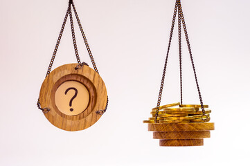 Two scales with yellow coins and a question mark inverted on a white background. The concept of how...