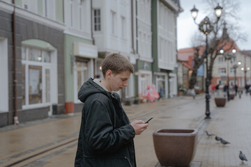 addicted to a mobile phone, a teenager looks at a smartphone in an urban environment