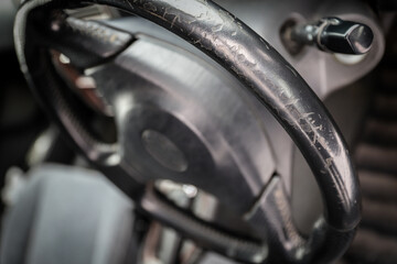 Threadbare automotive black leather steering wheel of old auto close-up