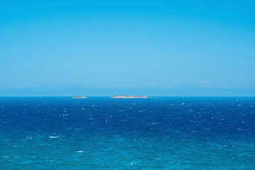 seascape on a windy sunny day with islands and distant barely visible shore on the horizon