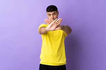 Young Colombian man isolated on purple background making stop gesture with her hand to stop an act