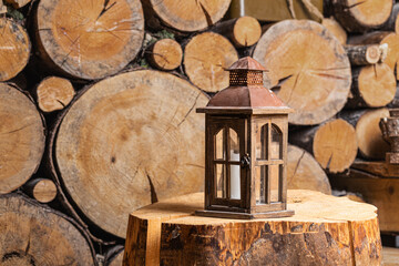 An old portable lantern stands in a rustic wood-burning room. There is a door on the lantern to replace the candle. Composition in retro style