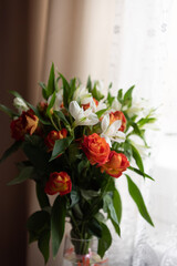 A delicate bouquet of red and white flowers in front of the window