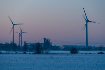 Windräder drehen sich im Industriegebiet Rothensee in Magdeburg, während die untergehende Sonne...