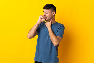 Young Colombian man isolated on yellow background coughing a lot