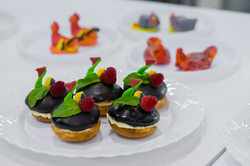 Assortment of delicious fresh shortcrust tart cakes with cream, chocolate and berries on white plate for sale at restaurant, cafe, bakery. Dessert, culinary, sweet food and confectionery concept