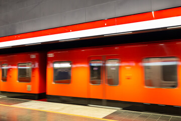 Orange subway train in motion at an underground station in Helsinki, Finland.