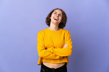 Young English woman isolated on purple background looking up while smiling