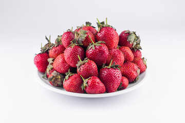 Fresh strawberry on white ceramic plate on white background.