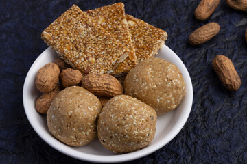 Indian sweetMithai on deep blue background for Makar Sankranti Lohri Gajak Also Known As Gur Gajjak, Gazak, Gachak Til Patti Or Papdi Chikki Made Of til sesame seed Jaggery Gud Almond Badam Pistachio