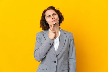 Young English woman isolated on yellow background having doubts while looking up