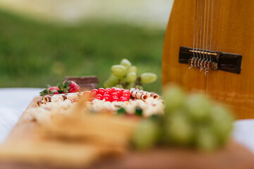 frutas y golosinas en una tabla de madera desenfocada y una guitarra