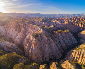 Aerial view over the colorful eroded badlands of the Gorafe desert, los Coloraos, at sunset,...