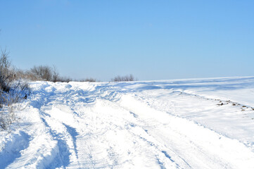 Fototapeta na wymiar Snowy winter road in the field. Deep snow