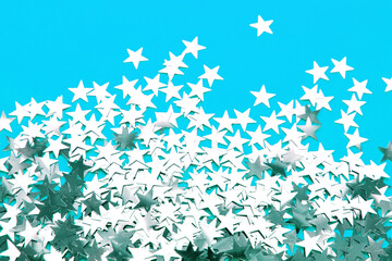 Background of shiny silver little stars on blue background. Christmas concept. Glitter texture.