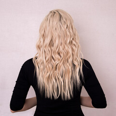 Naklejka premium Female back with long, curly, natural blonde hair, on grey background 