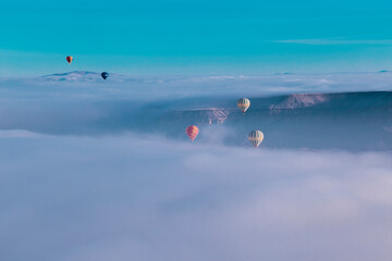 Hot air balloons flying over spectacular Cappadocia. Beautiful view of hot air balloons floating in sunrise blue sky over the mountain landscape of fairy chimneys