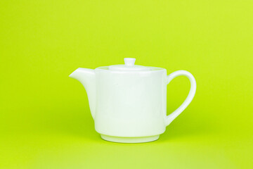 White ceramic kettle teapot on green background. Tea concept with white teapot