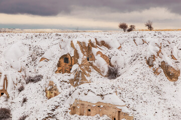 Beautiful landscape of pigeons are flying in Cappadocia pigeon valley, Uchisar, Turkey. Flock of fluffy pigeons on white snow in Pigeon Valley in winter 