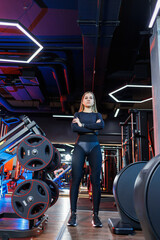 Fototapeta na wymiar An experienced fitness trainer of a sporty woman stands in the gym and thinks about an exercise plan. Diet and weight loss concept. Personal trainers women in the gym