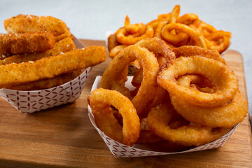 A view of a variety of deep fried appetizers, featuring onion rings, zucchini, and curly fries. - obrazy, fototapety, plakaty