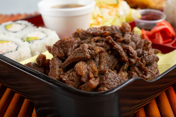A view of a bento box, featuring teriyaki beef.