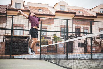a young man jumping to hit a ball in a paddle tennis match.