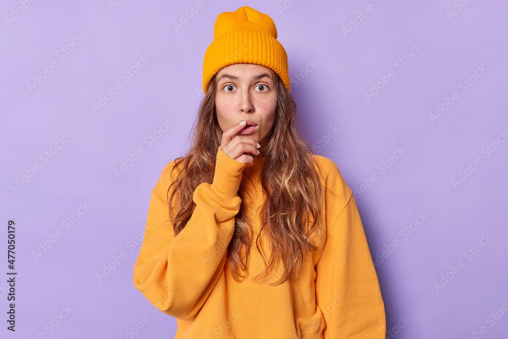 Wall mural stunned young woman with long hair feels impressed cannot believe her eyes stares stupefed at camera